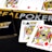 Poker-themed setup featuring a deck of cards on a table with the words 'REAL POKER' visible. Two cards, the King of Clubs and Jack of Diamonds, are prominently displayed. The design is vibrant, with detailed illustrations on the cards.